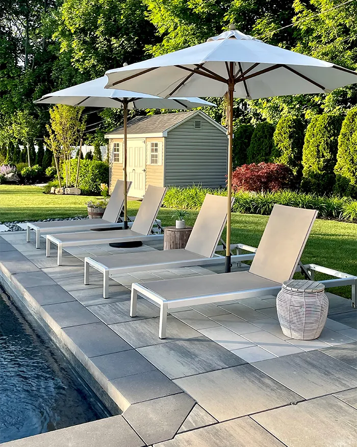 patio chairs under umbrellas by a pool